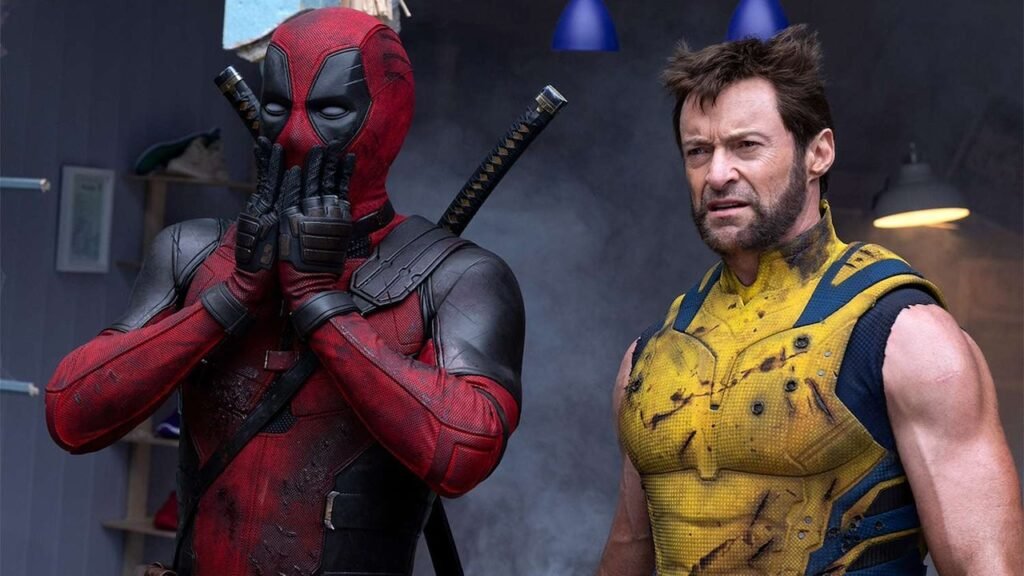 Cena cômica de Deadpool e Wolverine: Deadpool faz uma piada, olhando diretamente para a câmera, enquanto Wolverine reage com uma expressão de irritação cômica. O cenário inclui elementos exagerados e referências humorísticas ao universo Marvel, refletindo o tom satírico do filme.