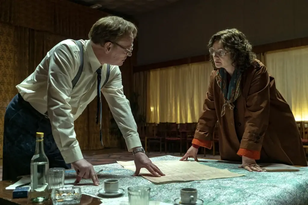 Imagem mostrando Ulana Khomyuk e Valery Legasov em uma discussão séria, representando cientistas que trabalharam para entender o desastre de Chernobyl.